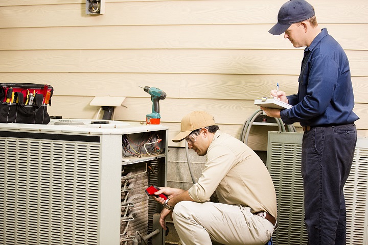HVAC professionals repairing a central air conditioning unit